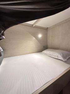 een groot wit bed in een kleine kamer bij Bollywood Beach Hostel in Dubai