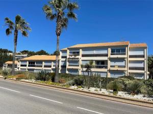 a white building with palm trees in front of a street at Studio cabine climatisé in Sanary-sur-Mer