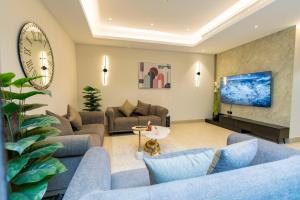 uma sala de estar com sofás azuis e um relógio em Riyadh Boulevard Luxury Apartment em Riyadh