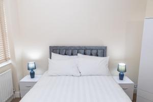 a bedroom with a white bed with two blue lamps at Fortune 24 house in Rainham