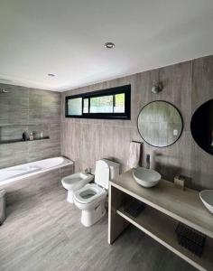 a bathroom with two sinks and a toilet and a tub at Casa Las Magnolias Villa General Belgrano in Villa General Belgrano
