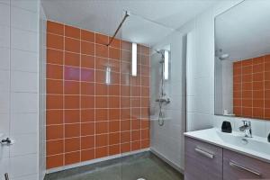 ein orangefarbenes und weißes Badezimmer mit einer Dusche und einem Waschbecken in der Unterkunft Cosy flat close to the city centre and beaches in Montpellier