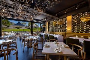 a restaurant with tables and chairs and wine bottles at Steenberg Hotel & Spa in Tokai