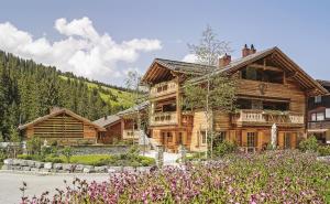 una gran casa de madera con flores delante en Lech Lodge - 3 Chalets und eine "Gute Fee", en Lech am Arlberg