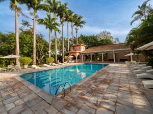 a pool at a resort with palm trees at Carlton Suítes Limeira in Limeira