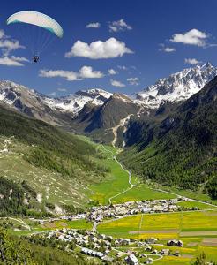 a paraglider flying over a valley in the mountains at chalet panoramique in Ceillac
