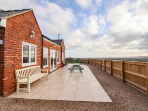 a brick building with a bench and a table on a patio at Border View Lodge in Welshpool