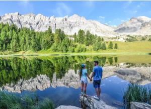 a man and woman standing on a rock near a lake at chalet panoramique in Ceillac