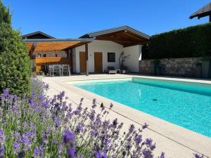 a swimming pool in front of a house with purple flowers at Apartment Sonntagskind in Seekirchen am Wallersee