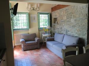 a living room with a couch and chairs and a stone wall at La Luna Nel Pozzo in Castiglion Fibocchi