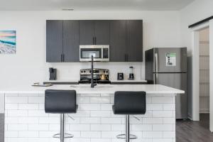 eine Küche mit einer Theke mit 2 Stühlen und einem Kühlschrank in der Unterkunft Corporate Housing by MGM in Whitestown