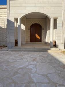 a building with a wooden door and a stone patio at مزرعة المدائن in Madain Saleh