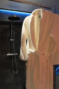 a white robe hanging on a rack in a bathroom at L'Ecrin duplex balnéo & Sauna in Troyes
