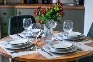 una mesa de madera con platos y vasos y un jarrón con flores rojas en DejaVu en Novi Sad