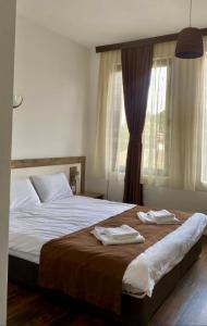 ein Schlafzimmer mit einem großen Bett mit zwei Handtüchern darauf in der Unterkunft БЯЛАТА КЪЩА in Kirkowo