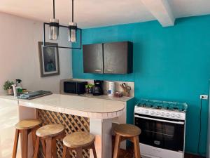 cocina con paredes azules y encimera con taburetes en Casa Pacific Blue Hawaii, en Chiquimulilla