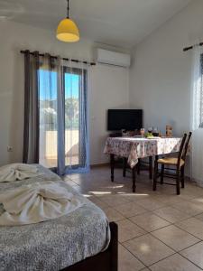 a living room with a table and a tv and a bedroom at Irida Apartments -EX BLAZIS HOUSE in Almyrida