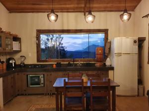 een keuken met een tafel, een koelkast en een raam bij Euetu na Lapinha da Serra in Santana do Riacho