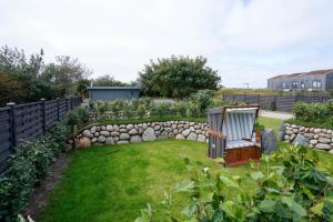 a garden with a chair and a rock wall at MeerVerliebt B in Hörnum