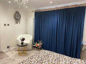 a bedroom with a bed and a blue curtain at Beautiful place to live near Heathrow Windsor Legoland & Free Parking Onsite in Burnham
