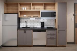 a kitchen with a refrigerator and a counter with a microwave at Candlewood Suites Sugarland Stafford in Houston