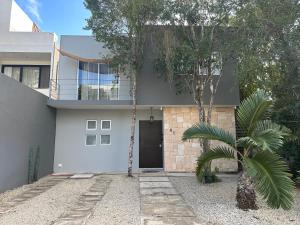 a house with a palm tree in front of it at Zen Home in Tulum