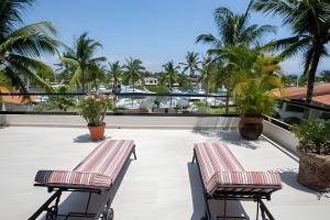 dwa krzesła na dachu budynku z palmami w obiekcie Grand Marina Villas w mieście Nuevo Vallarta