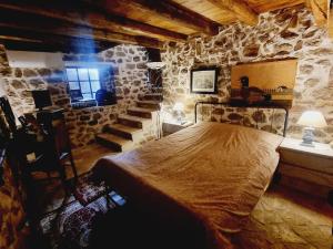 1 dormitorio con cama y pared de piedra en Βίλα Ελιά Παραδοσιάκο σπίτι στην Αμφίκλεια, en Amfikleia