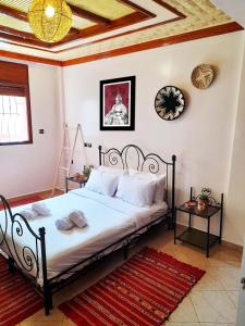 1 dormitorio con 1 cama y reloj en la pared en Olympe Surf & Yoga en Tamraght Ouzdar