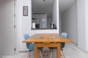 jadalnia z drewnianym stołem i niebieskimi krzesłami w obiekcie Cozy apartment perfect for couples SmartTv+WiFi w mieście Fuengirola