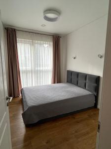 1 dormitorio con cama y ventana grande en Slenio Apartamentai, en Kaunas
