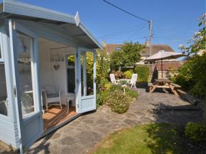 a white shed with a door and a patio at 3 Bed in Burton Bradstock DC055 in Burton Bradstock