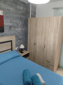 sypialnia z niebieskim łóżkiem i drewnianą szafką w obiekcie La casita de la abuela w Maladze