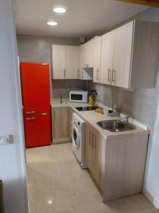 eine Küche mit einer Spüle und einem roten Kühlschrank in der Unterkunft La casita de la abuela in Málaga