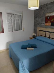 1 dormitorio con cama azul y almohadas azules en La casita de la abuela, en Málaga
