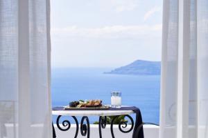 a plate of food on a table in a room with the ocean at San Antonio - Small Luxury Hotels of the World in Imerovigli