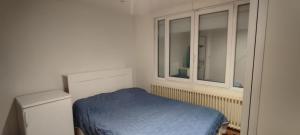 ein Schlafzimmer mit einem blauen Bett und einem Fenster in der Unterkunft didounet in Sevran