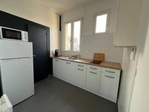 uma cozinha com armários brancos e um frigorífico branco em Grand Paris cocooning à 5 minutes de la gare em Pavillons-sous-Bois