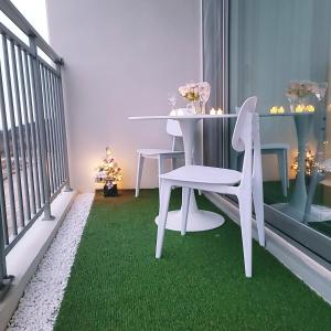 un balcone con tavolo e sedie bianchi su moquette verde di 영종 러블리 하우스, 오션뷰 테라스 3룸 6인실 a Incheon
