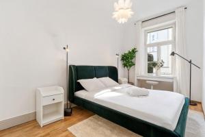Schlafzimmer mit einem großen Bett mit einem grünen Kopfteil in der Unterkunft Luminous Luxe - White and Gold in Luxemburg (Stadt)