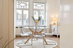 ein Esszimmer mit einem Glastisch und Stühlen in der Unterkunft Luminous Luxe - White and Gold in Luxemburg (Stadt)