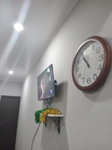 a clock and a television on a wall at New Saburtalo Star in Tbilisi City