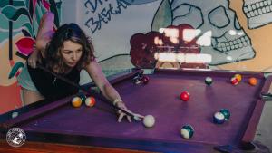 a woman playing a game of snooker at Surf Town Hostel in San Juan del Sur