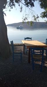 a wooden table and chairs with a boat in the water at Kamares beach room 7 in Kamáres