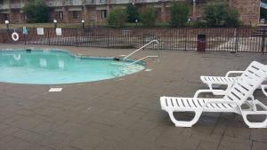 a swimming pool with two white benches next to at Red Carpet Inn in Hot Springs