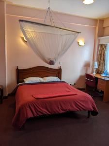een slaapkamer met een bed met een rode deken bij Metro Hotel in Nairobi