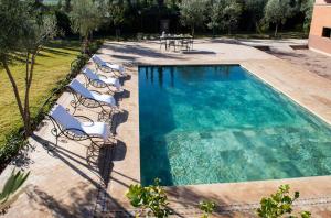 a swimming pool with chairs and a swimming pool at Ferme D'hôte Zomorroda in Marrakech