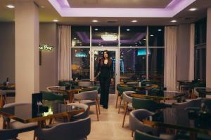 a woman standing in a room with tables and chairs at Wellness Spa Hotel Jola in Banja Luka