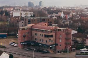 ein großes Backsteingebäude mit auf einem Parkplatz geparkten Autos in der Unterkunft Wellness Spa Hotel Jola in Banja Luka