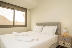 - une chambre avec un grand lit blanc et 2 serviettes dans l'établissement Cozy Spot II near the beach, à Ayiá
